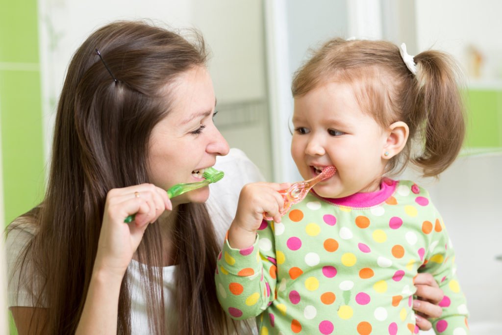 Image of mother and toddler brushing teeth together