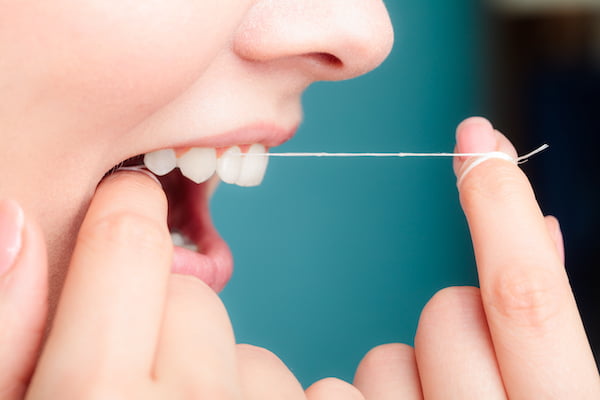 Close up image of woman flossing her teeth